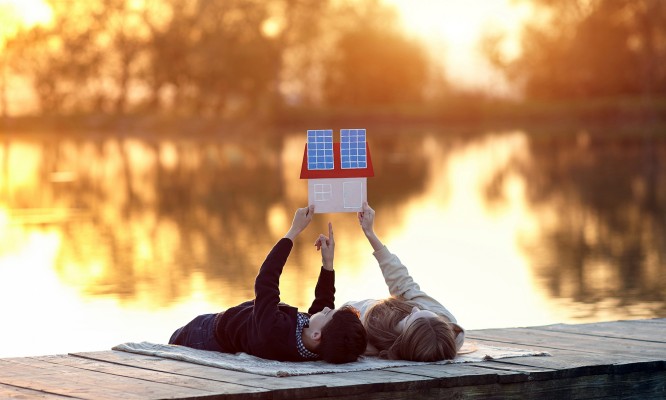 Happy couple of children dreaming of a house with solar panels. Solar energy panel concept. Alternative energy.